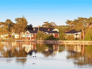 A residential area with houses along a calm lake, a dock, and a clear sky.
