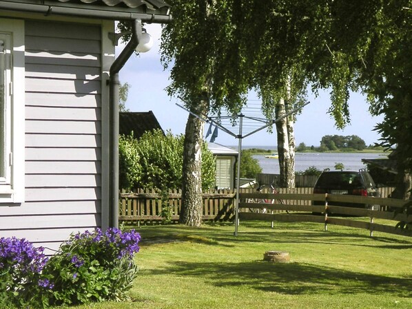 A house with a fenced yard, a tree, and a body of water in the background.