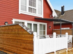 Una casa roja con detalles blancos, un muelle de madera y un patio cubierto.