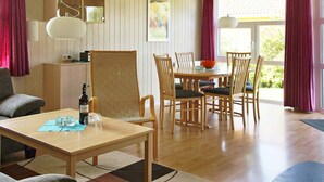 Ein gemütliches Wohnzimmer mit Holztisch, Stühlen, einer Couch und einem Essbereich mit Tisch und Stühlen.