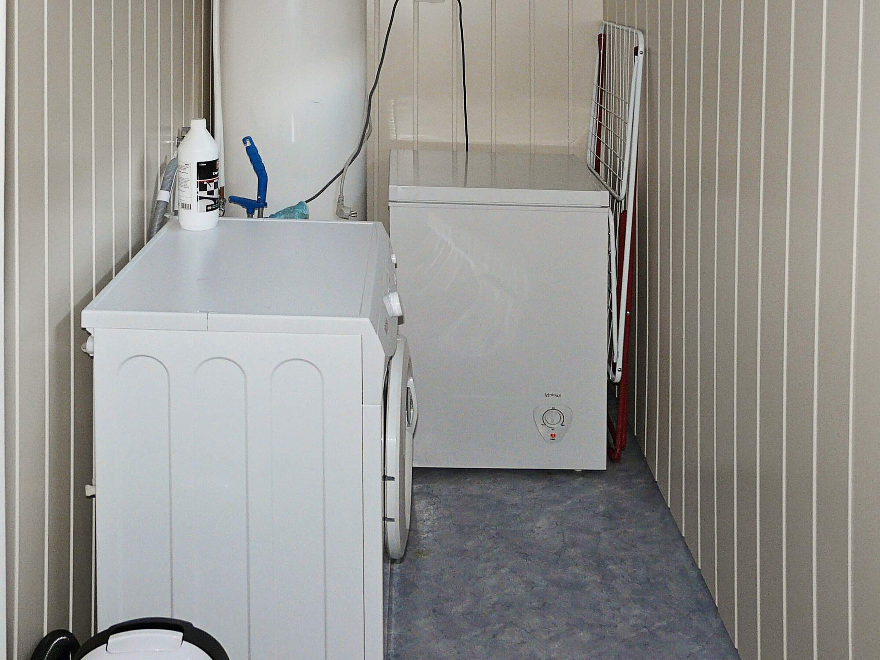 A narrow hallway with two white appliances, one on each side, and a radiator on the right.