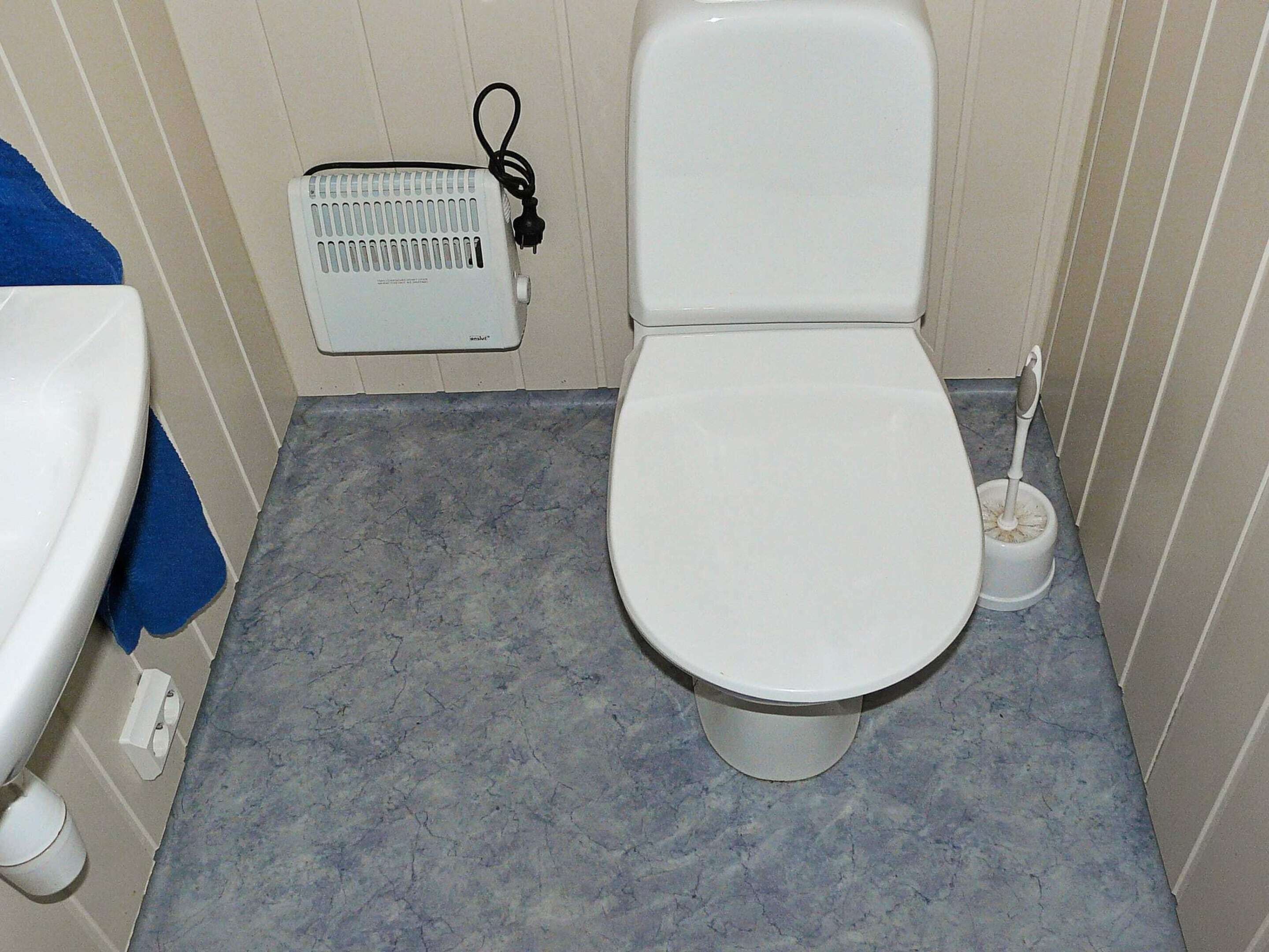 Een badkamer met toilet, wastafel, handdroger en vloerverwarming.