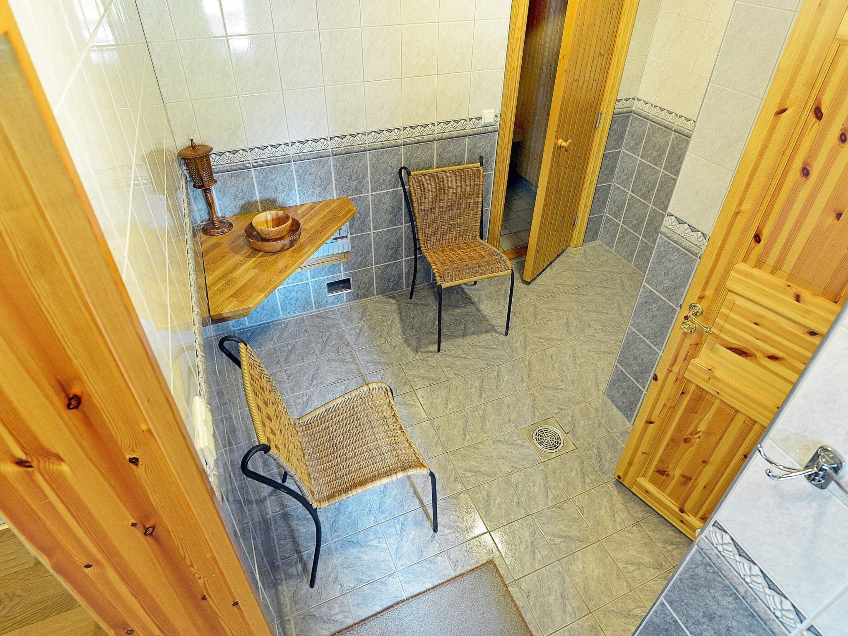 A bathroom with two wicker chairs, a wooden bench, and a tiled floor.