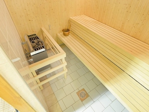 A sauna room with a bench, a heater, and a bucket. - Holiday Home in Mellerud (Mellerud)