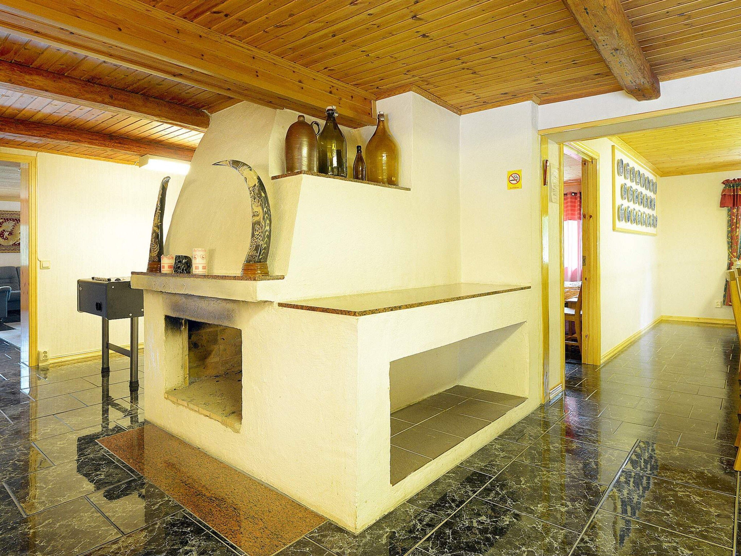 A kitchen with a built-in oven, a wooden ceiling, and a tiled floor.