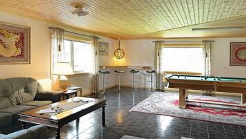 Ett rum med ett biljardbord, en soffa, ett soffbord och en lampa.