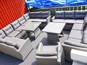 A sectional sofa with attached side tables and a cushioned bench, arranged on a gravel patio. - Holiday Home in Mellerud (Mellerud)