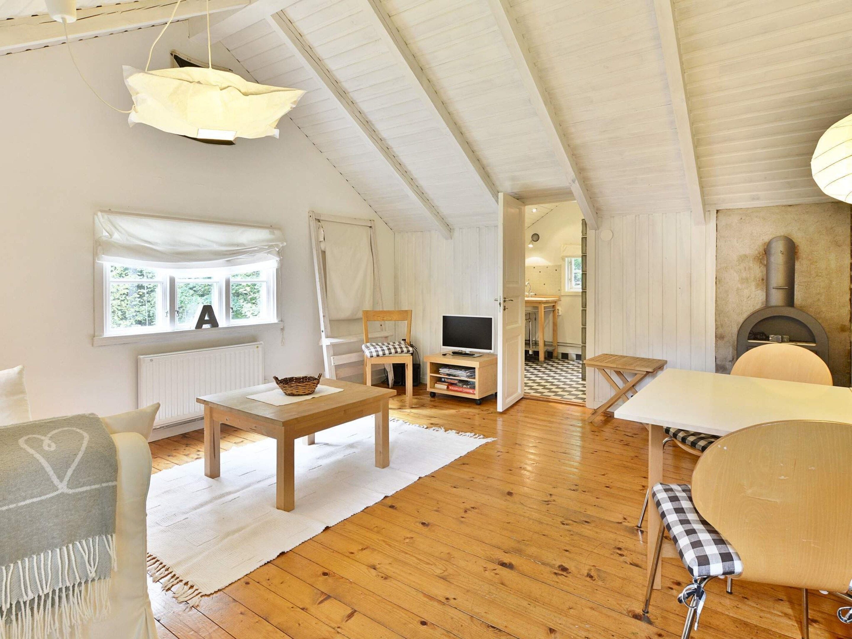 A cozy living room with a fireplace, wooden furniture, and a view of the outdoors.