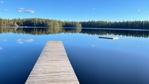 A wooden pier extending into a calm lake with a forested shoreline in the background. - Holiday Home in Hallabro (Hallaröd)
