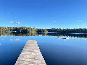 A wooden pier extending into a calm lake with a forested shoreline in the background. - Holiday Home in Hallabro (Hallaröd)