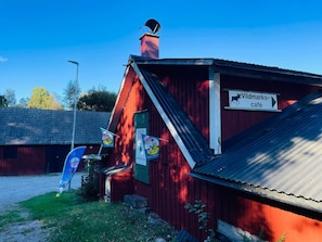 Een rood gebouw met een bord waarop 'Wildmarks-café' staat en een blauwe vlag met een logo.
