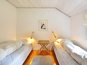 A room with two single beds, a small wooden table, and two wall-mounted lamps. - Holiday Home in Hallabro (Hallaröd)