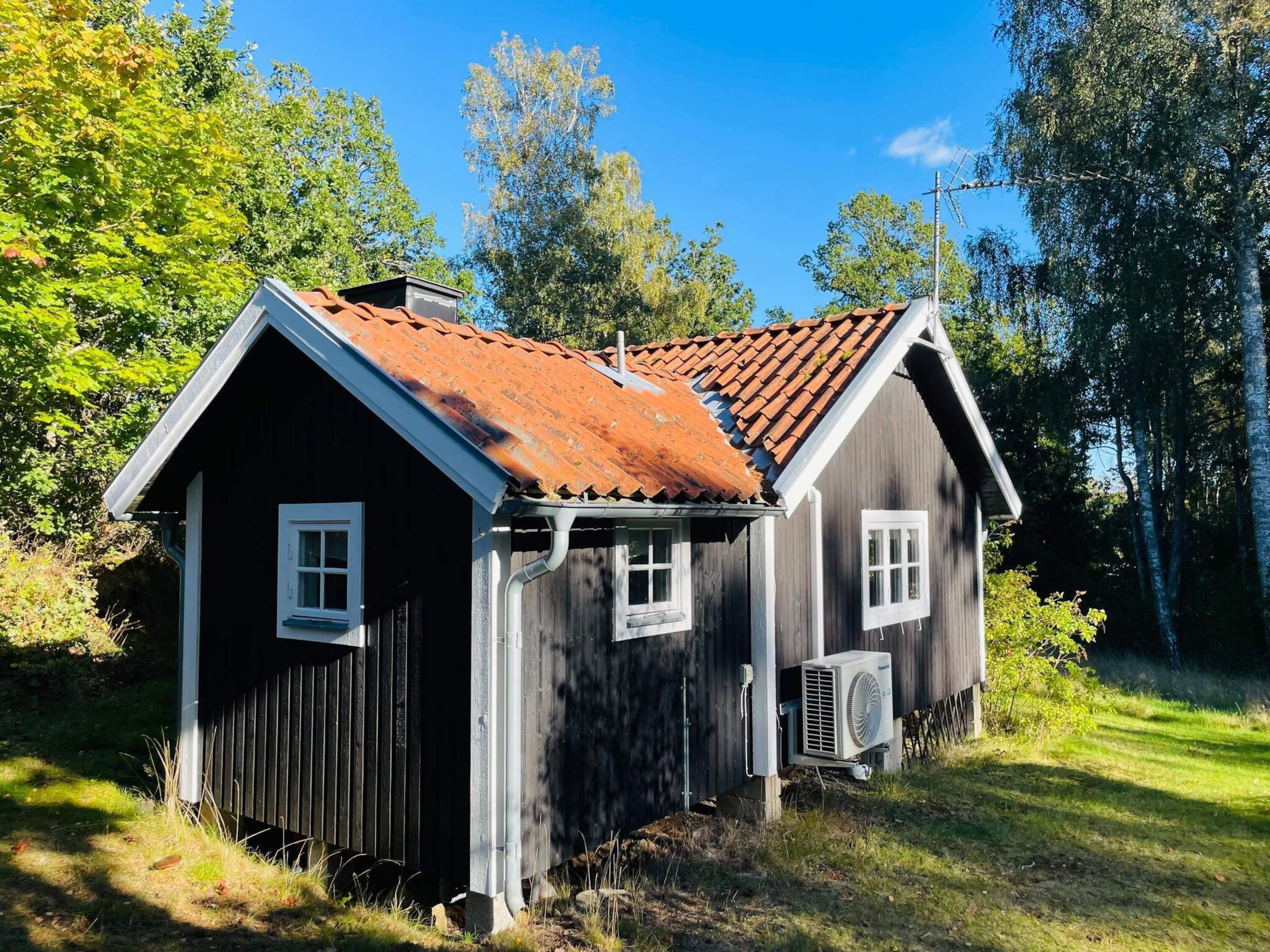Une cabane en bois avec un toit en pente, une fenêtre et un appareil de climatisation.