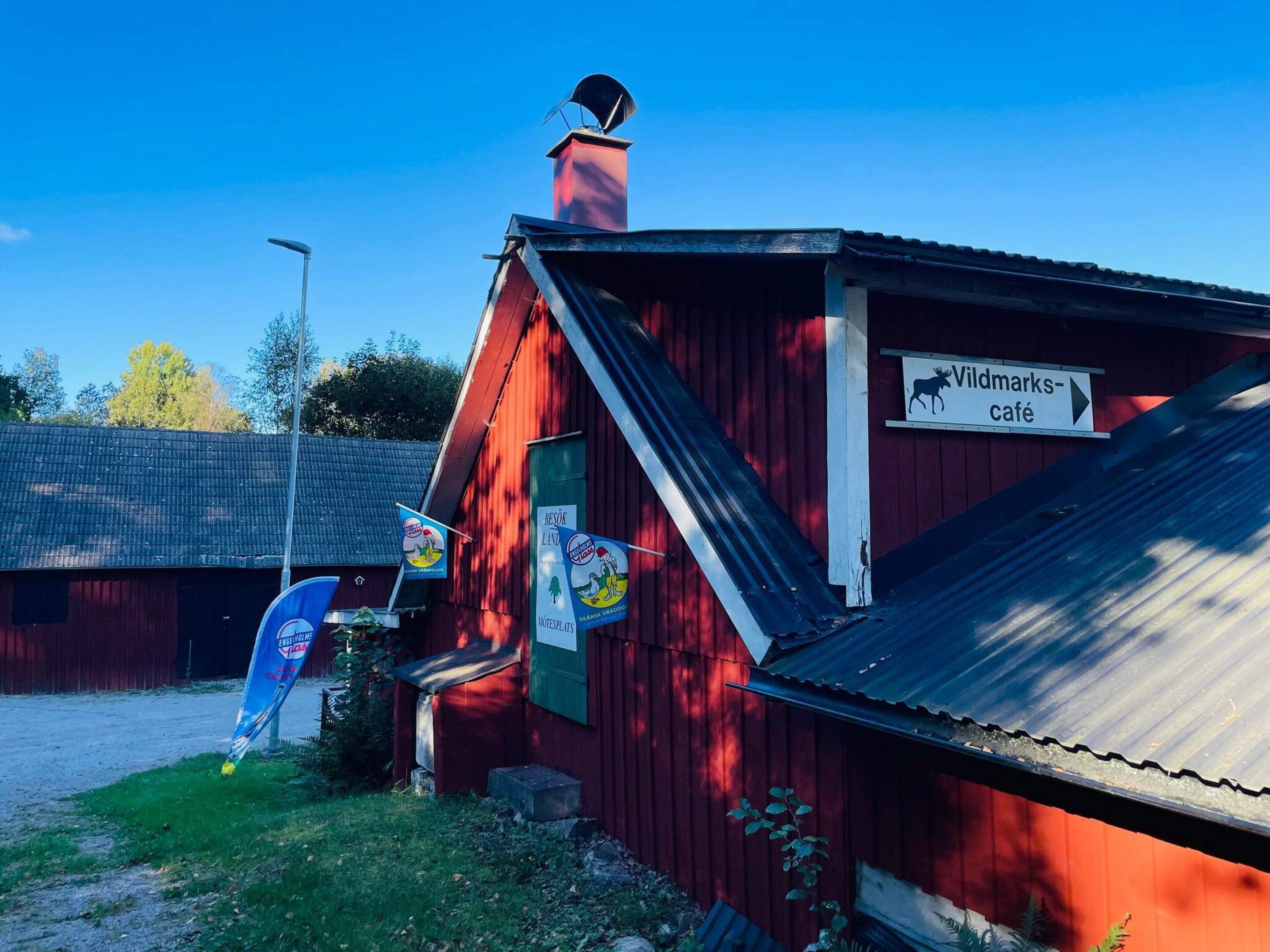 Um edifício vermelho com uma placa indicando 'Wildmarks-café' e uma bandeira azul com um logotipo.