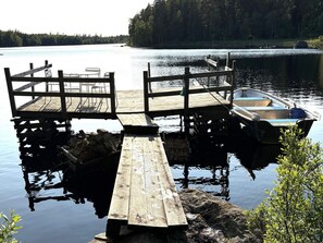A wooden dock extending into calm water with a small boat docked at the end. - Holiday Home in Hallabro (Hallaröd)