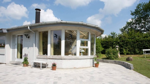 A house with a curved patio, large windows, and a chimney.