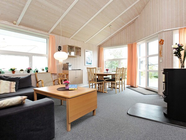 A cozy living room with a sofa, a coffee table, and a dining area with chairs and a table.