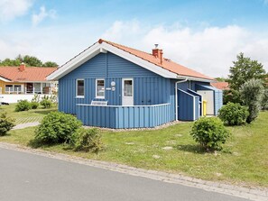 A blue house with a red roof, a small porch, and a number '23' on the door.