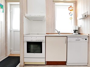 A kitchen with a built-in oven, a dishwasher, and a coffee maker on the countertop.