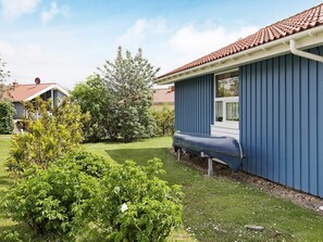 Um imóvel residencial com fachada azul, telhado de telhas vermelhas e um jardim bem cuidado.
