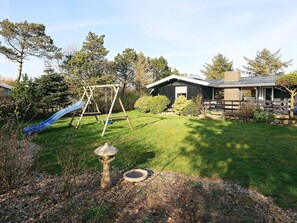 A backyard with a swing set, a bird bath, and a house with a porch. - 4 Star Holiday Home in Hurup Thy (Hurup Thy)