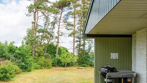 Un espace extérieur abrité, doté d’un barbecue et d’une terrasse en bois.