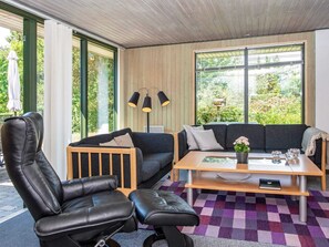 A modern living room with a sofa, two black leather chairs, a coffee table, and a large window with a view of greenery. - 6 Person Holiday Home in Ebeltoft (Ebeltoft)