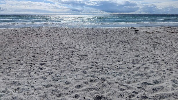 Une plage avec un ciel dégagé et une mer calme.