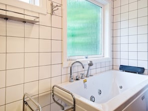 Een moderne badkamer met een bad, een raam en een douche.
