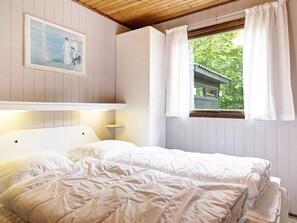 A bedroom with a bed, a painting on the wall, and a window with curtains.