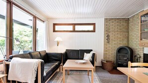 A cozy living room with a black leather sofa, a wooden coffee table, and a fireplace. - 4 Star Holiday Home in Aakirkeby (Akirkeby)