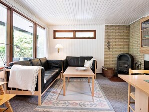 A cozy living room with a black leather sofa, a wooden coffee table, and a fireplace. - 4 Star Holiday Home in Aakirkeby (Akirkeby)