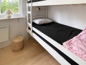 A bunk bed with a black mattress and a pink blanket, a white pillow, a lamp on the window sill, and a woven basket on the floor. - 6 Person Holiday Home in Kopingsvik (Kopingsvik)