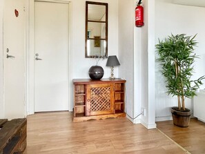 A wooden console table with a decorative mirror, a lamp, and a potted plant in a corner. - 6 Person Holiday Home in Kopingsvik (Kopingsvik)
