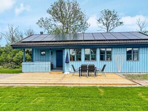 A blue building with a covered patio area, a door, and windows. - 6 Person Holiday Home in Kopingsvik (Kopingsvik)