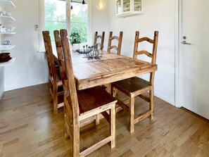 A dining table with six wooden chairs, a potted plant, and a metal candle holder on the table. - 6 Person Holiday Home in Kopingsvik (Kopingsvik)
