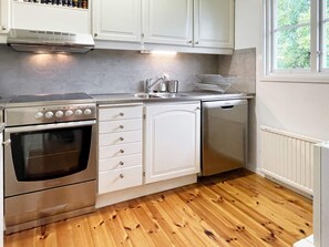 A kitchen with a stainless steel oven, white cabinets, a dishwasher, and a window with a view of greenery. - 6 Person Holiday Home in Kopingsvik (Kopingsvik)