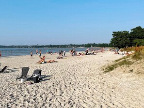 A sandy beach with people sunbathing and swimming, and a clear view of the water. - 6 Person Holiday Home in Kopingsvik (Kopingsvik)