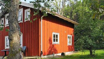 A red wooden house with white windows and a porch.