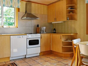 A compact kitchen with a stove, oven, and wooden cabinets. - Holiday Home in Uddevalla (Uddevalla)