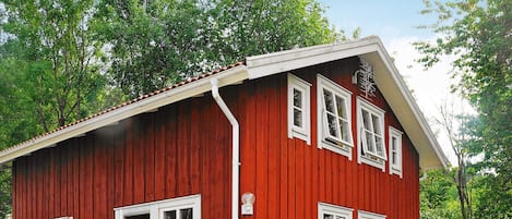 A red wooden building with a sloped roof, white trim, and multiple windows.