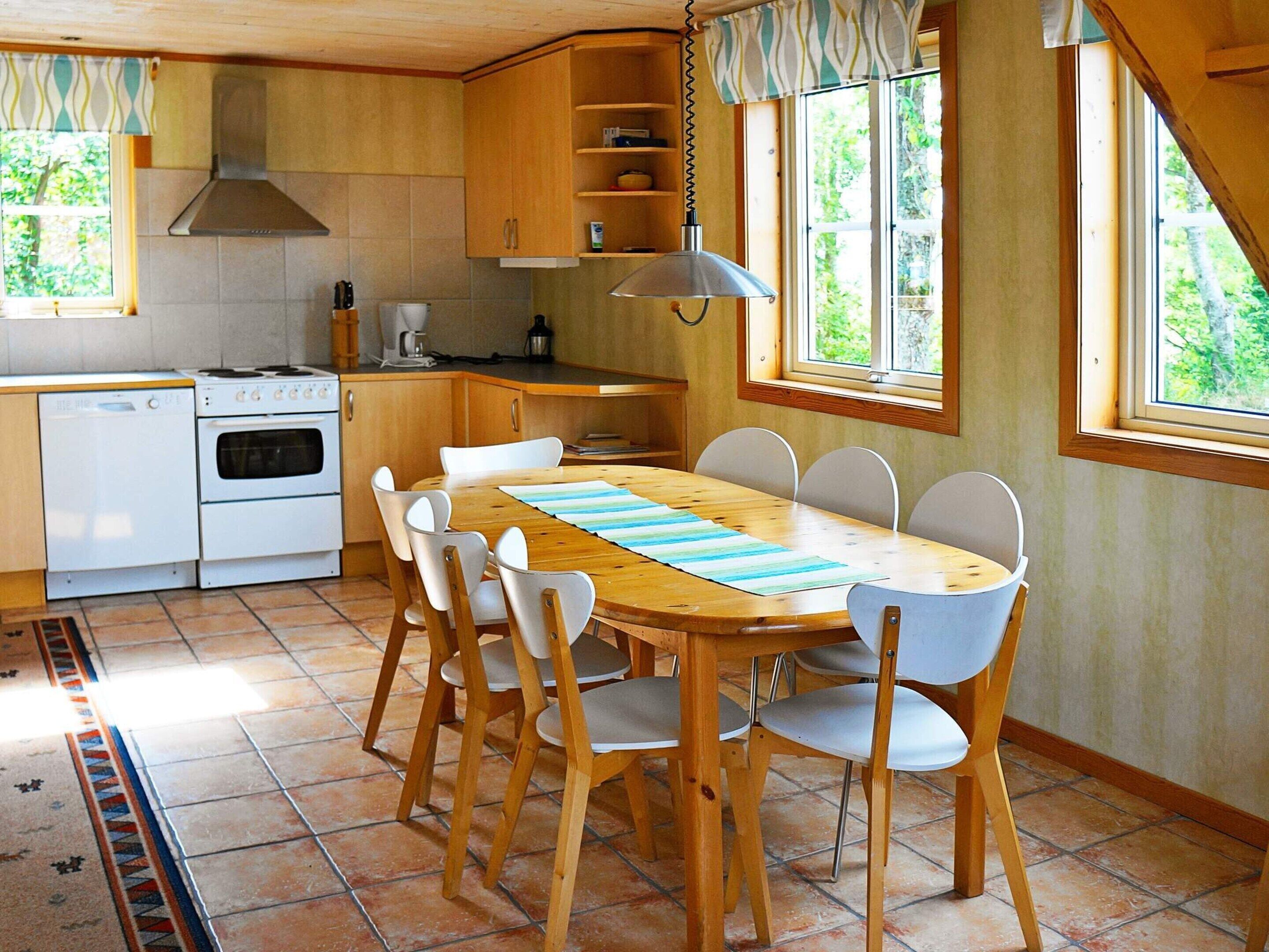 A kitchen with wooden cabinets, a stove, and a dining table with chairs.