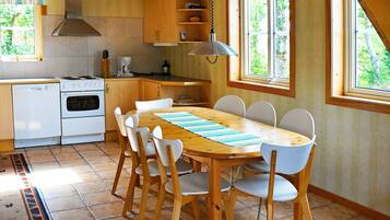 A kitchen with wooden cabinets, a stove, and a dining table with chairs.