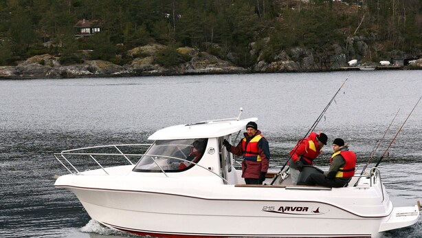 A white boat named '216 Arvor' with three people wearing life jackets, fishing on a calm lake with a forested shore in the background. - Holiday Home in Jelsa (Suldal)