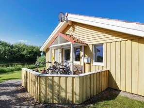 En byggnad av trä med en överbyggd veranda, en satellitmottagare och cyklar parkerade utanför.