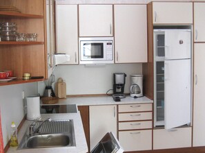 Una cocina compacta equipada con microondas, cafetera, refrigerador y pileta.