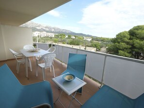 A balcony with a table and chairs, a small table with a bowl, and a view of buildings and trees. - Nice apartment for 8 people with pool, A/C, WIFI, TV and balcony (Ulldecona)