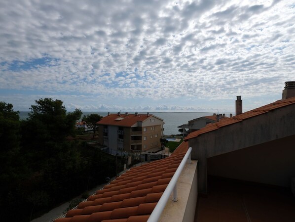 A balcony with a red-tiled roof overlooking a body of water and buildings. - Nice apartment for 8 people with pool, A/C, WIFI, TV and balcony (Ulldecona)