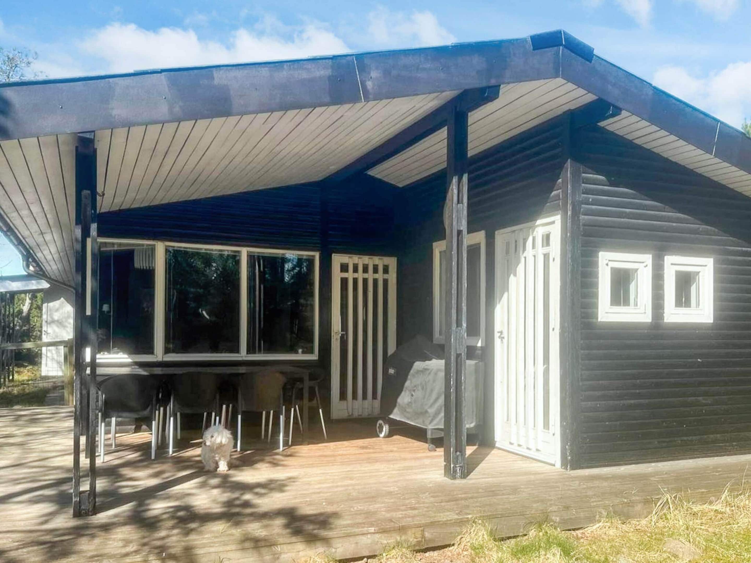 A modern house with a covered porch, a dining area, and a small deck.