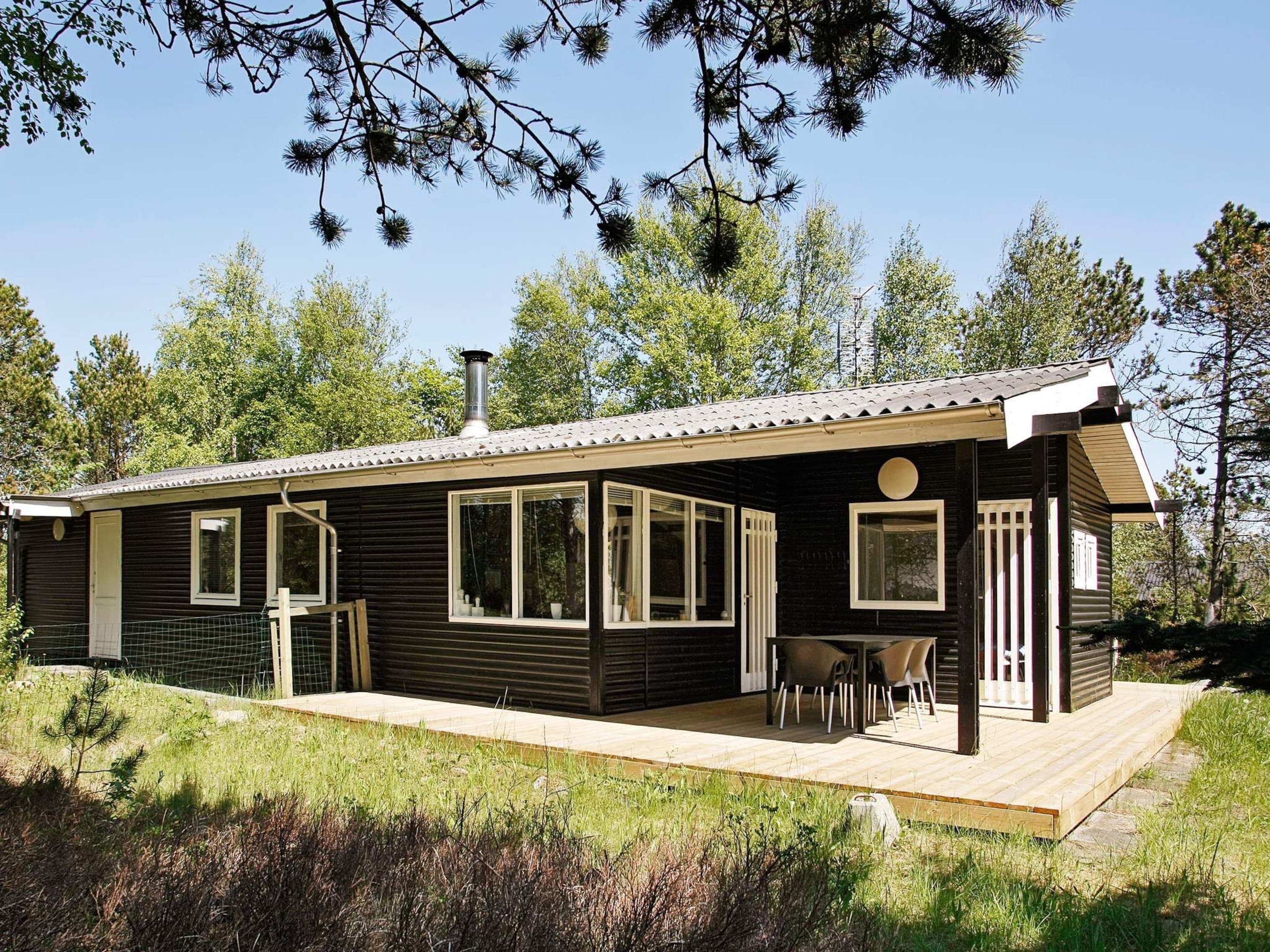 Een chalet met terras, grote ramen en schoorsteen.